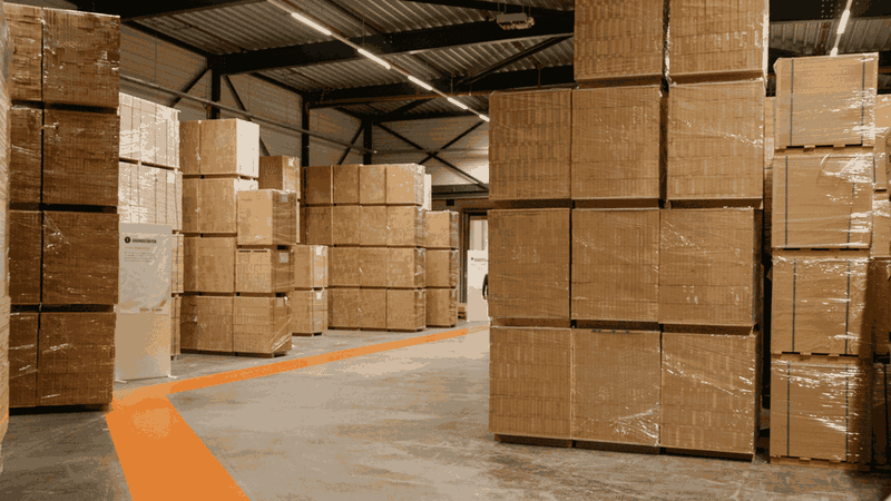 Warehouse aisle stacked high with cardboard boxes