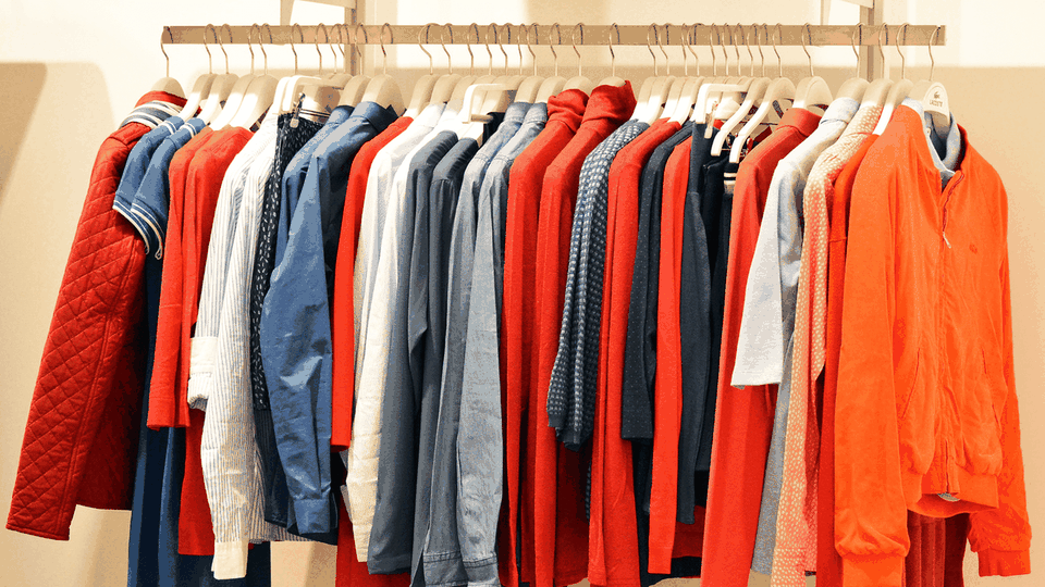 Shirts and jackets on wooden hangers along a clothing rail