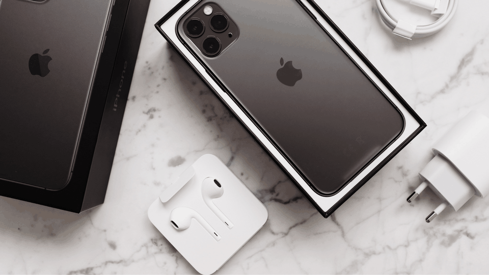Boxed phone, wired earphones and a charging plug on a marble surface