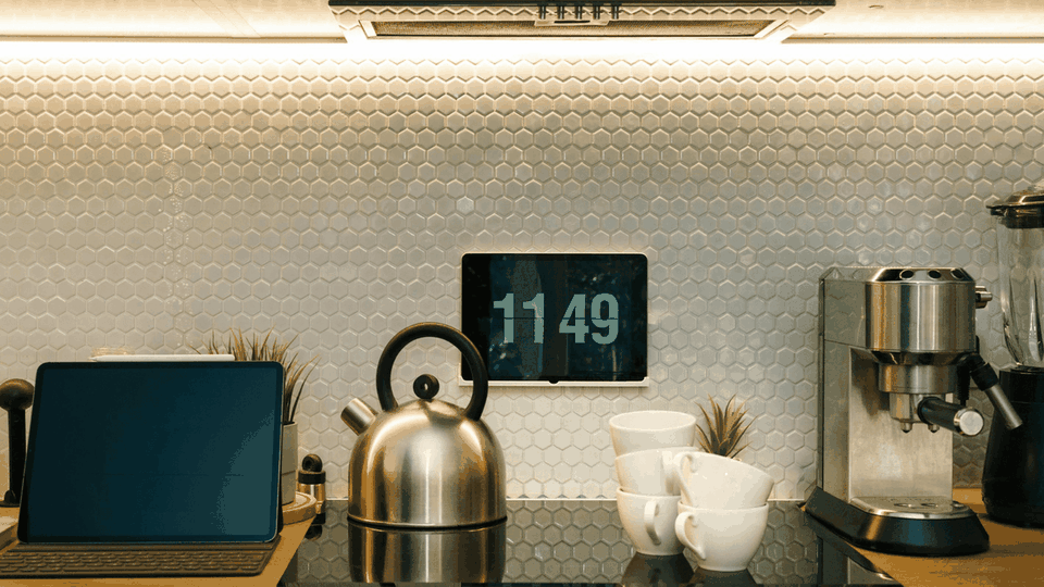 Kettle, espresso machine, tablet and stacked cups on a kitchen counter