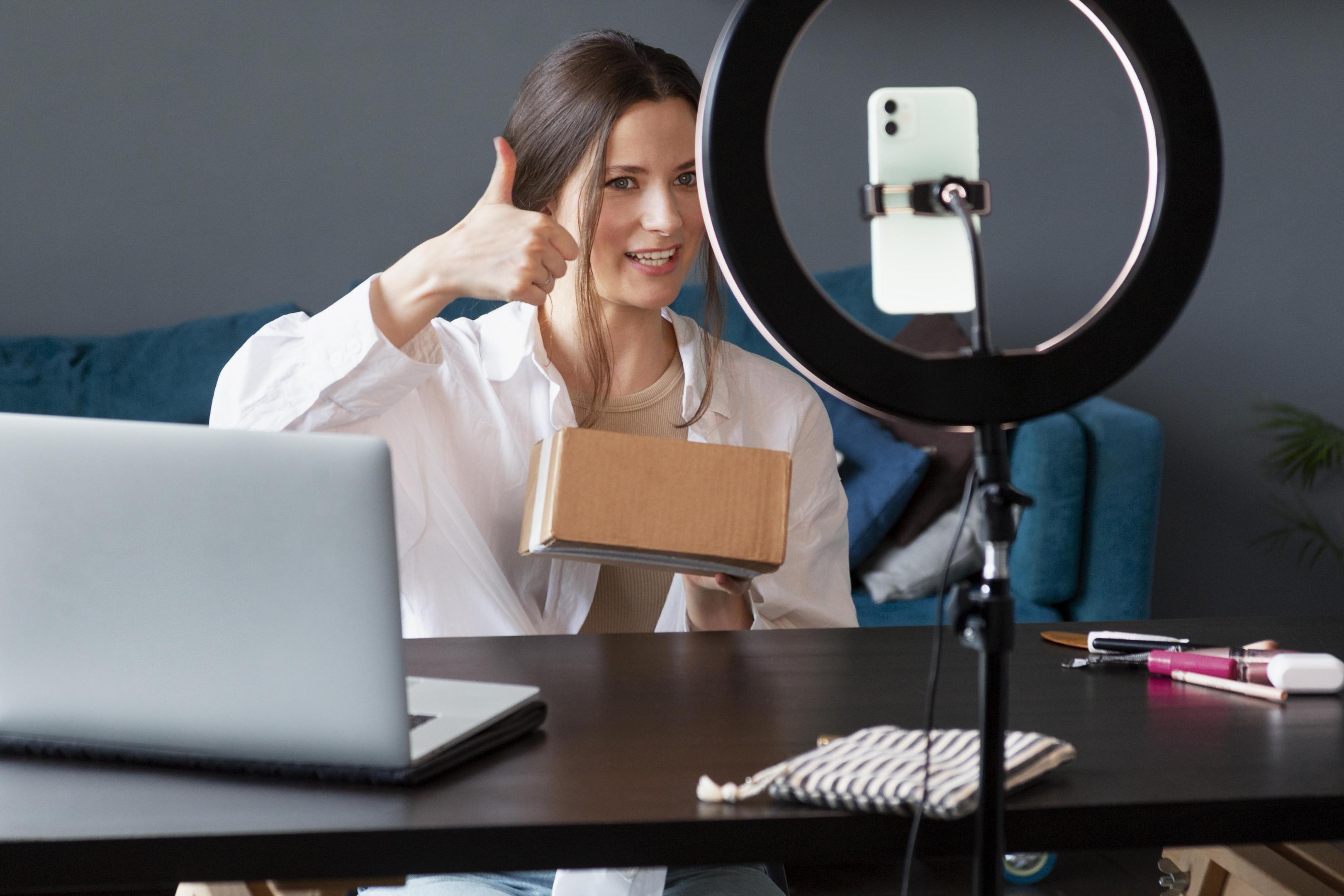 Seller filming a product video on a phone with a ring light and laptop